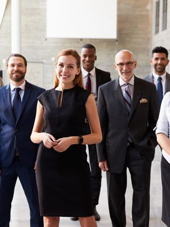 Group of professionally dressed people smiling in an office setting