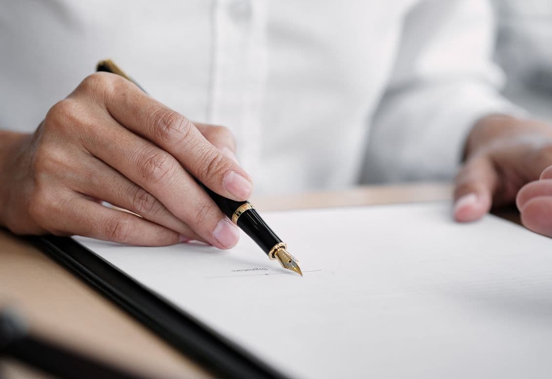 Close-up of a person signing a document with a fountain pen