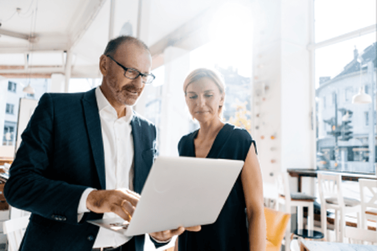 Man showing woman something on a laptop